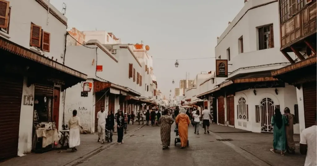 Locals and visitors walking a market street in Morocco, blending daily life and tourism morocco tours 2025