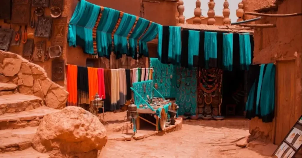 Colorful fabrics hanging in a desert kasbah market, symbolizing local craft and culture