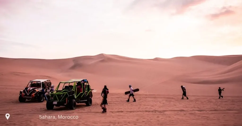 Group of travelers preparing to sandboard and drive buggies in Morocco’s desert