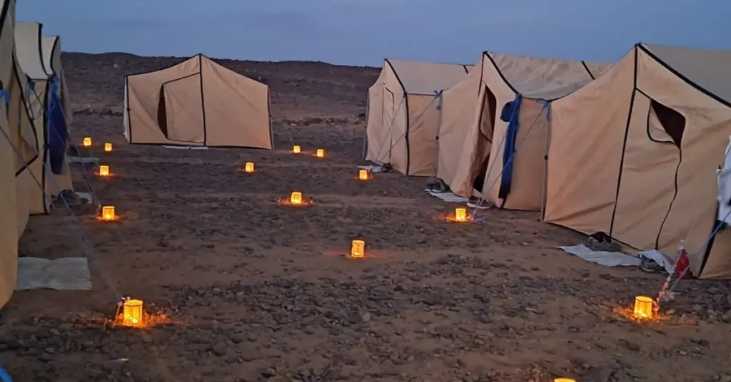 Morocco travel group campsite with lanterns and desert tents at dusk