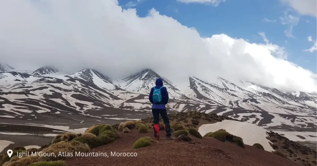 Hiker overlooking snow-covered Atlas Mountains near Ighil M’Goun
