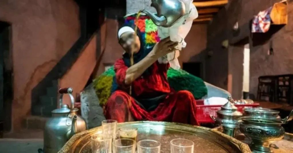 Moroccan woman pouring mint tea in traditional ceremony during a group tour